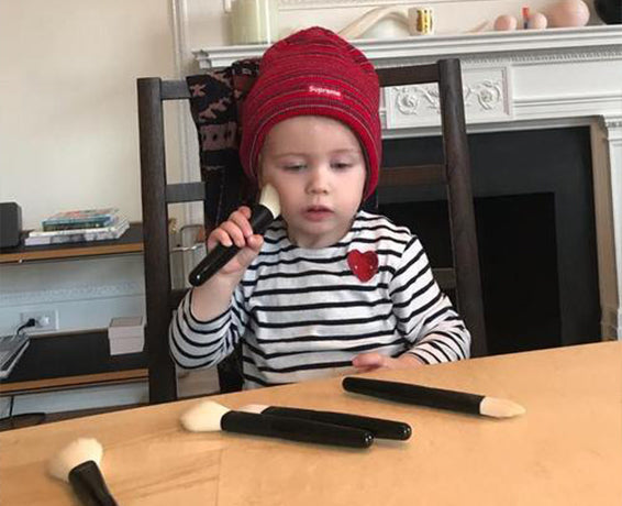 Gucci's daughter Petal plays with makeup brushes at the dining room table
