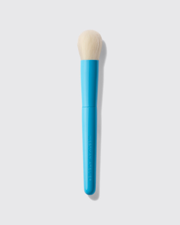 Blue makeup brush with beige bristle head on a light gray background