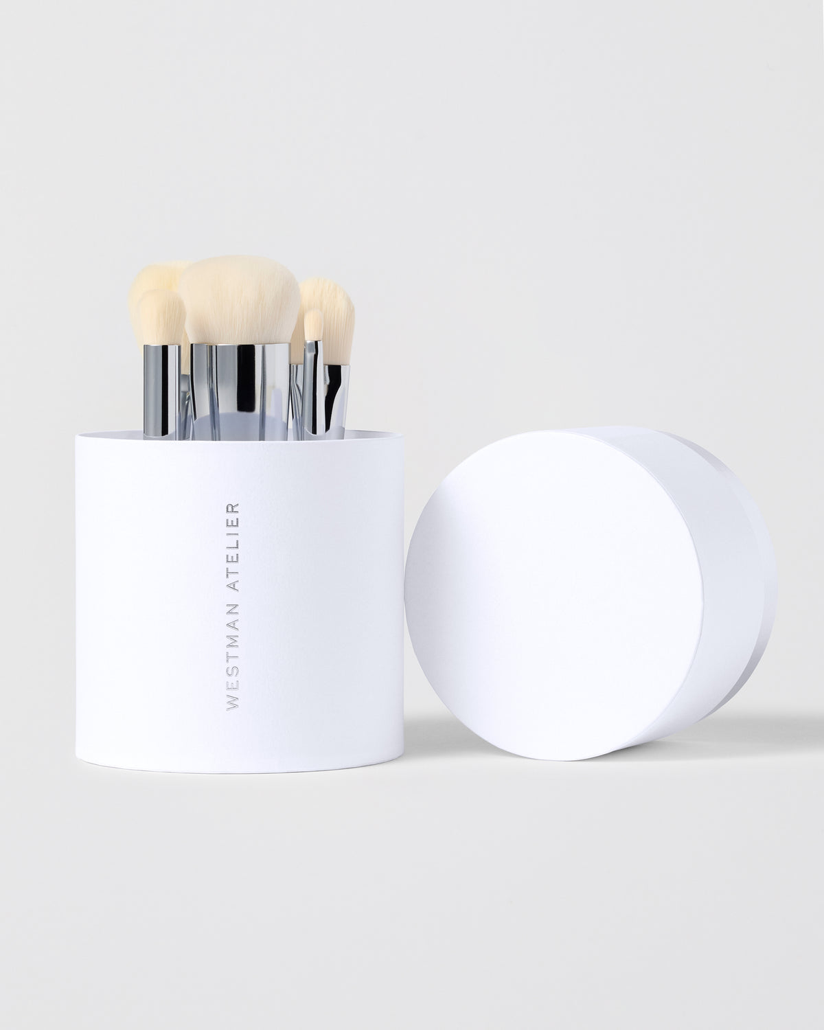 Set of makeup brushes in a white box on a light gray background