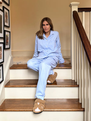 Woman in light blue pajamas sitting on a staircase.