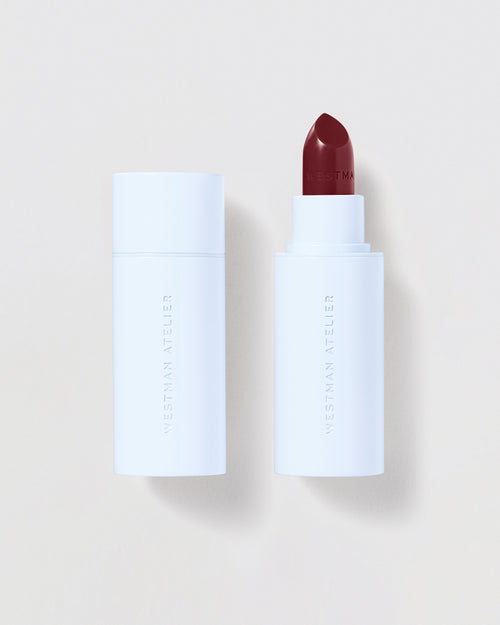 Lipstick with white casing and red shade on a light beige background