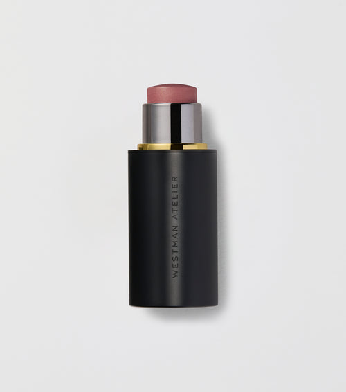 Black makeup stick with pink top on a light gray background.