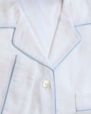 Close-up of white pajamas with blue piping and a button.